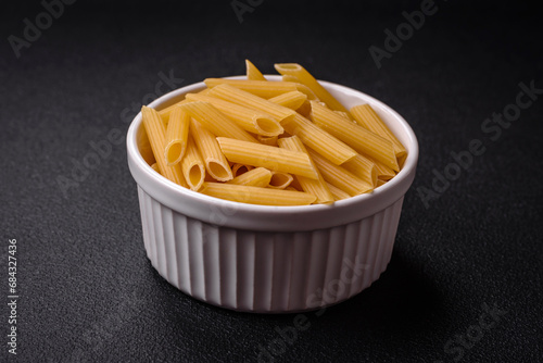 Raw penne pasta from whole grain wheat varieties with salt and spices