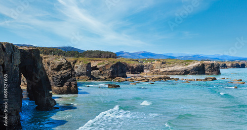 Natural rock arches on As Catedrais beach in low tide (Cantabric coast, Lugo (Galicia), Spain). Peoples are unrecognizable. Two shots stitch high-resolution panorama. photo