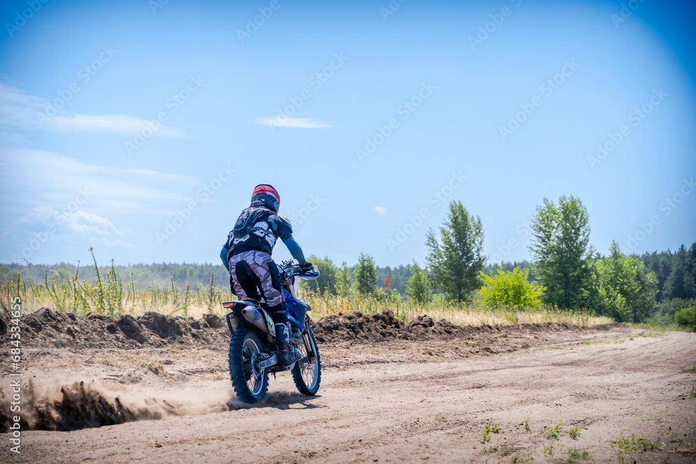 Enduro bike racer driving on dirt motocross dust track Enduro bike racer driving on dirt motocross dust track