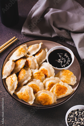 Crispy fried dumplings with soy sauce and sesame seeds on a plate vertical view