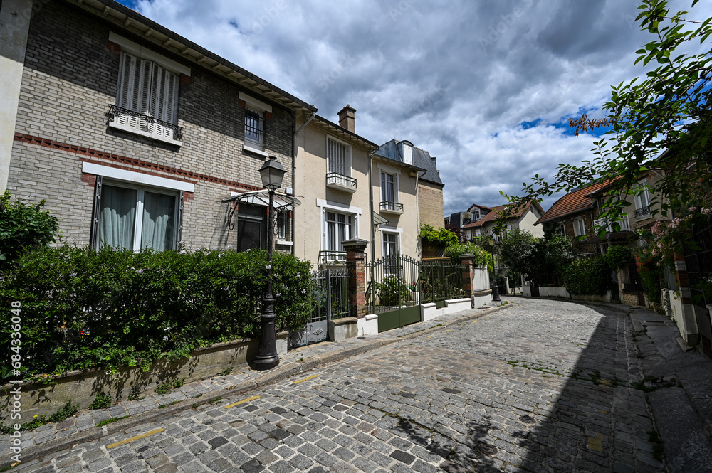 Paris, France.July 1, 2022. Paris to discover: the quiet and pretty neighborhood called Paris countryside. A fairytale place with small brick houses. The alley curves and hides between the houses.