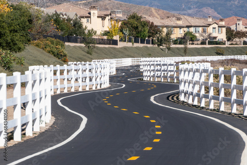 Suburban bike path with white fencing entertaining wiggles along the San Francisquito Creek Trail in Santa Clarita California. photo