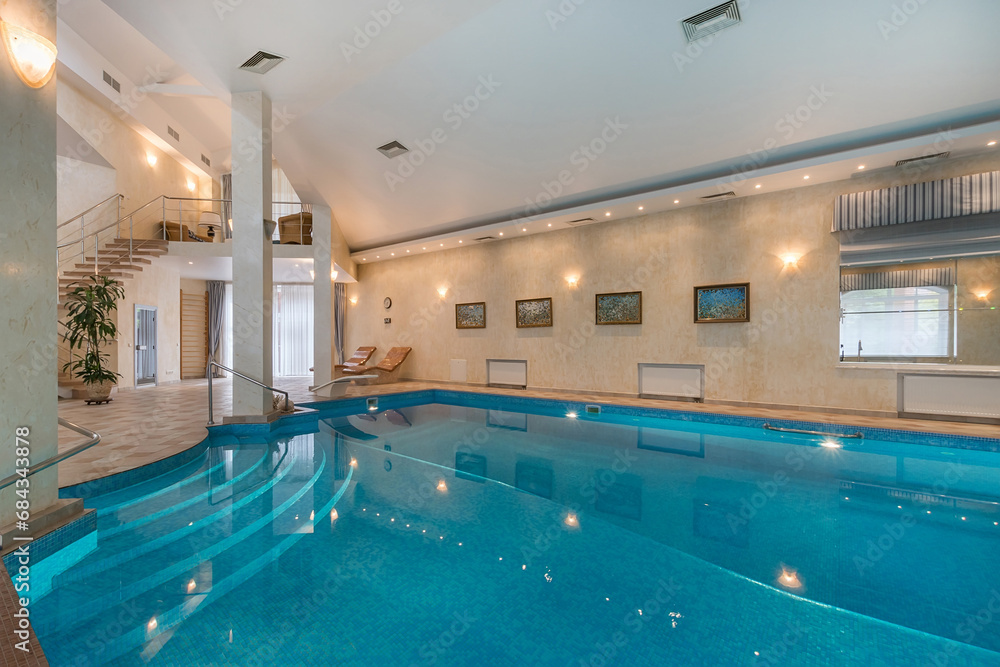 Private swimming pool in the interior of a luxury mansion. A room with a beautiful decor. A swimming pool with a wide staircase and convenient steps for descent.