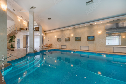 Private swimming pool in the interior of a luxury mansion. A room with a beautiful decor. A swimming pool with a wide staircase and convenient steps for descent.