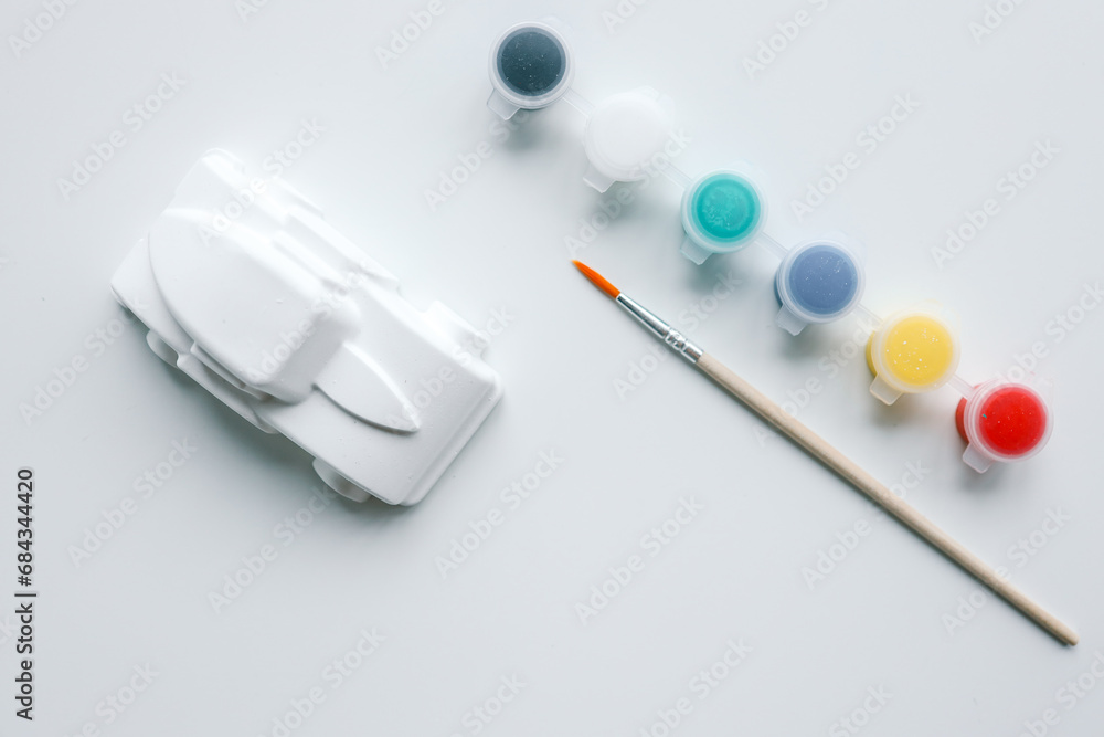 Child paints plaster figure with bright colors. Concept of children's creativity. Preschooler does needlework at home Child paints plaster figure with bright colors. Concept of children's creativity. Preschooler does needlework at home