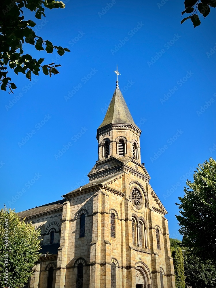 view of a small church with its clocger in a small village in France on a sunny summer day with a blue sky
