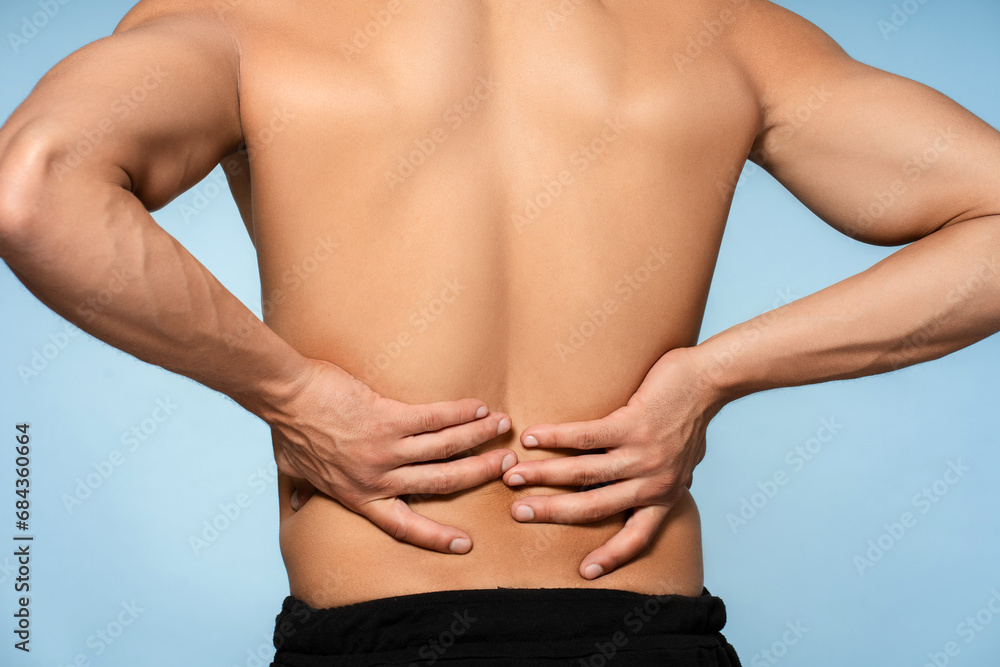 Back view African American man holding hands behind his back, lower back pain isolated on blue background Back view African American man holding hands behind his back, lower back pain isolated on blue background