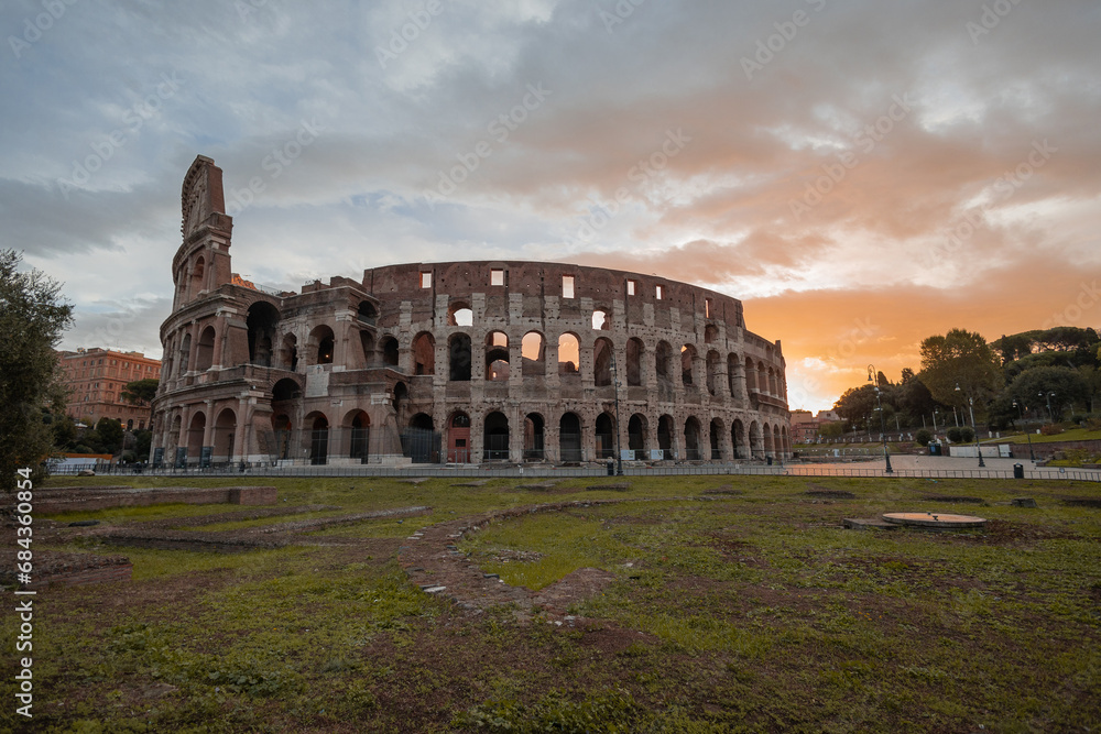 Early morning view of the colosseum in Rome, red and blue skies with sun just about to rise above the great famous amphitheatre. Autumn setting.
