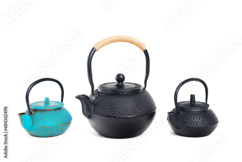 Three traditional cast iron teapots on white background.