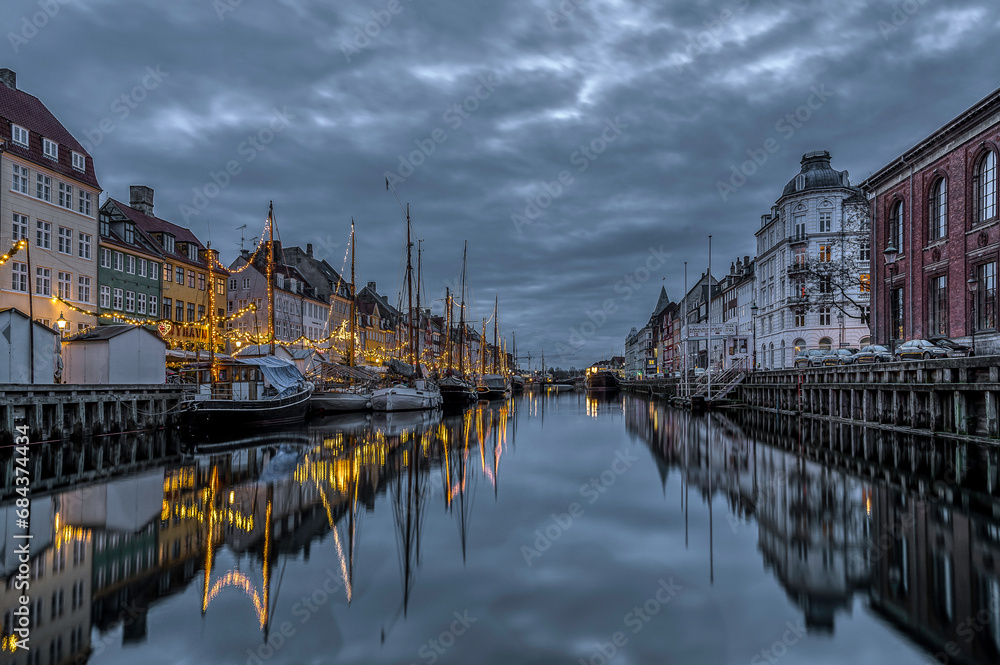Christmas decorations in Nyhavn are reflected in the water during the blue hour