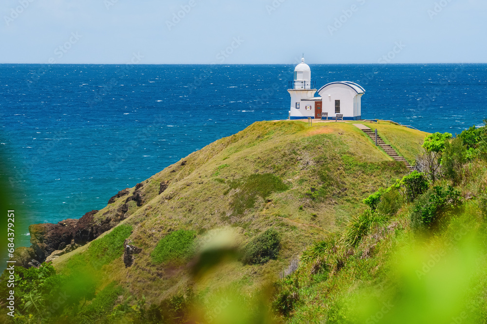 Port Macquarie Lighthouse, Australian coast with white lighthouse on green cliff top, seaside landscape with blue sea on summer sunny day.