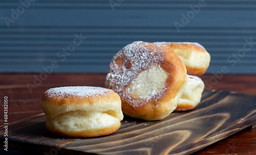 Berliner doughnuts with strawberry jam close-up on a wooden stand