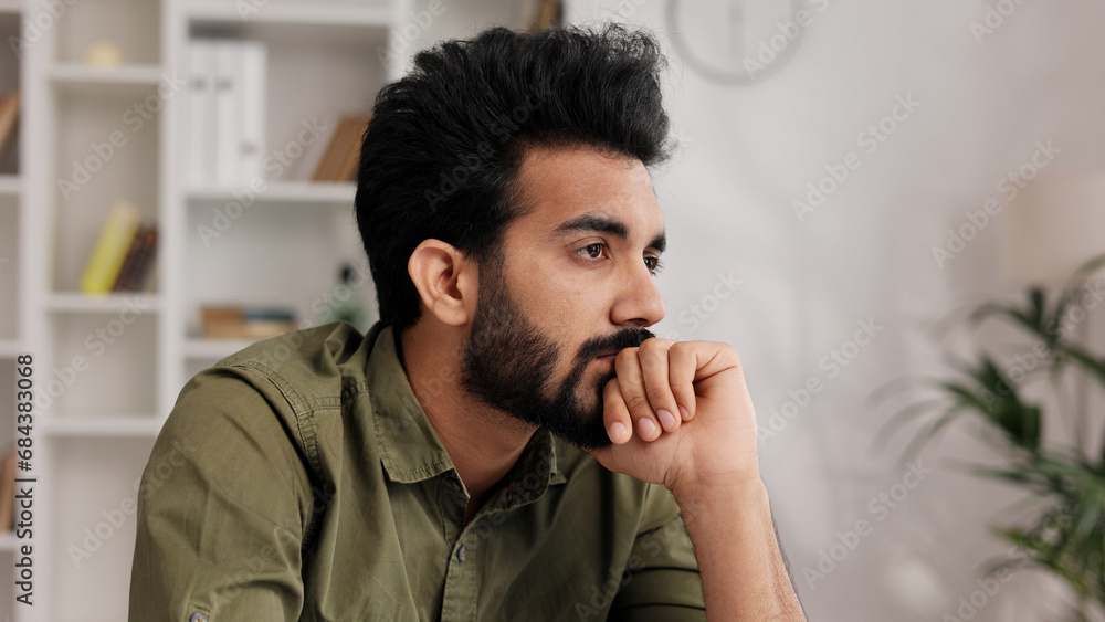 Bored millennial generation man sitting on sofa, feeling lonely at home. Unhappy young male suffering from negative thoughts, having depressive mood or problems in relations, regretting mistakes. Bored millennial generation man sitting on sofa, feeling lonely at home. Unhappy young male suffering from negative thoughts, having depressive mood or problems in relations, regretting mistakes.