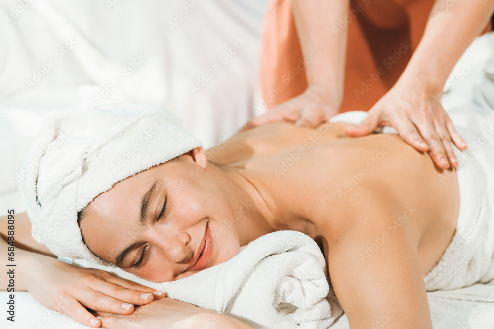 Beautiful caucasian woman having back massage by Thai professional masseur. Attractive woman feel deep in relaxation surrounded by aroma and essential oil. Relaxing and calm concept. Tranquility.