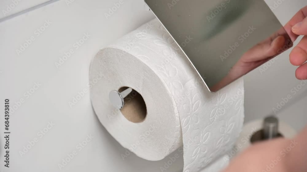 Toilet paper. Hands putting a new roll of toilet paper into the holder