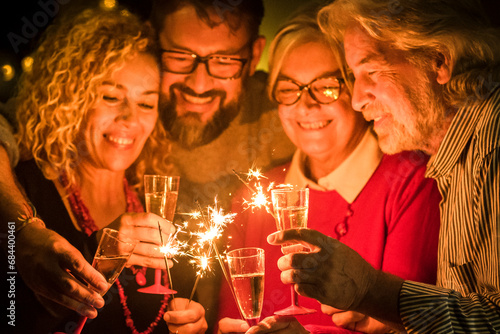 group of two seniors and two adults together having fun with sparlers the new year to celebrate - happy family with lights