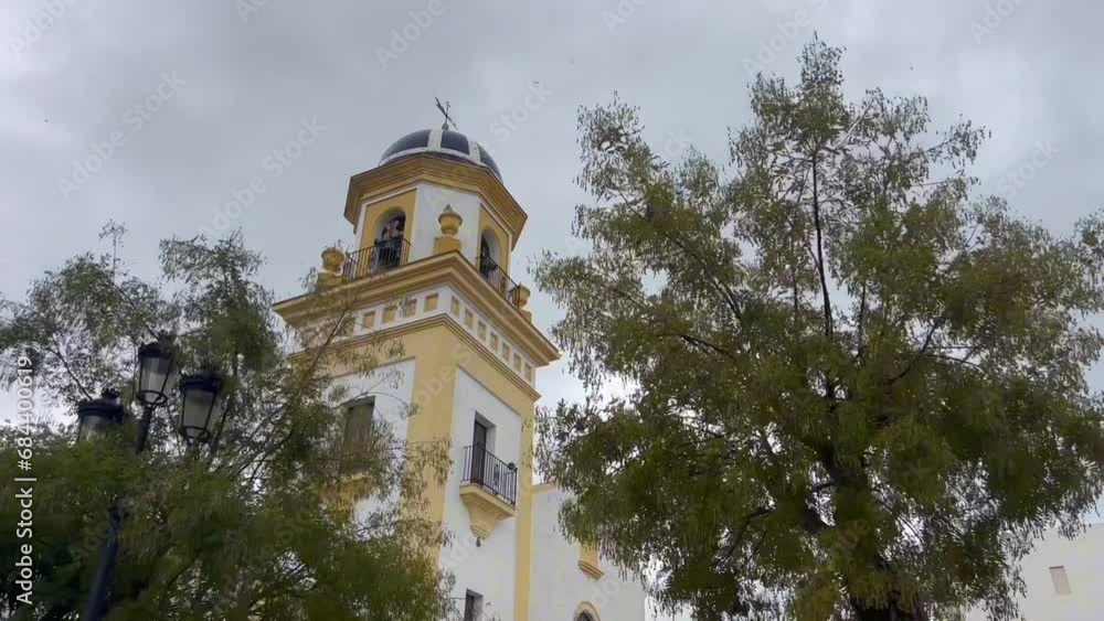 Revealing view of the church tower in Spain, rises majestically against the backdrop of a moody and cloudy sky during windy day. Architecture concept. Revealing view of the church tower in Spain, rises majestically against the backdrop of a moody and cloudy sky during windy day. Architecture concept.
