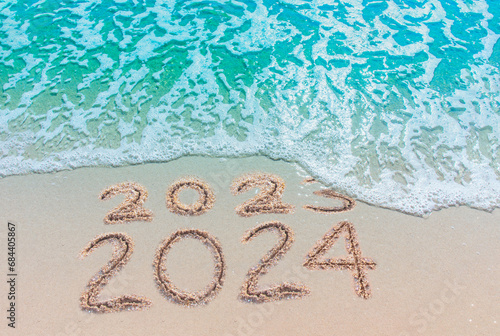 Message Year replaced by 2023 2024 written on beach sand background. Good bye 2023 hello to 2024 happy New Year coming concept. top view