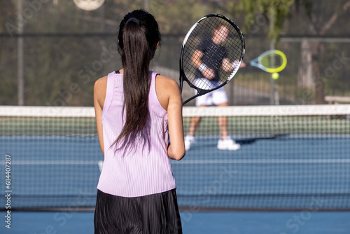 Two tennis players, a man and a woman practice together on the court by hitting the ball over the net. The workout is fun and active. 