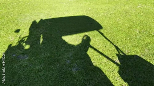 Shadow of a Golf Cart and a Golfer That Travel on the Green Grass on the Fairway in a Sunny Day on the Golf Course in Switzerland