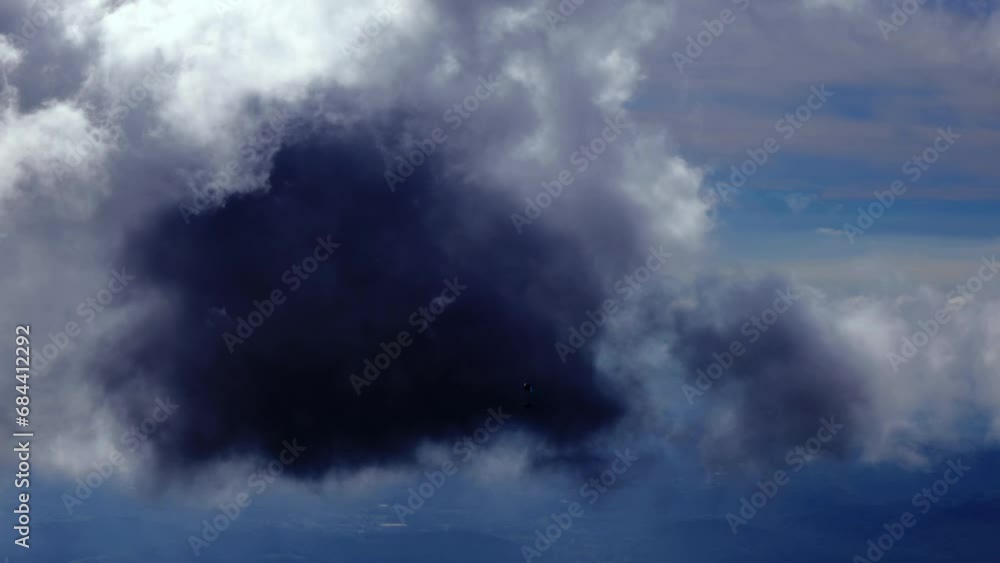 Aerial View over a Paraglider Flying in a Beautiful Dramatic Black Storm Cloud with Sunlight in Ticino, Switzerland, Europe Aerial View over a Paraglider Flying in a Beautiful Dramatic Black Storm Cloud with Sunlight in Ticino, Switzerland, Europe