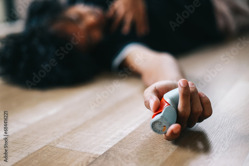 Man lying on the floor having asthma attack while holding asthma inhaler photo