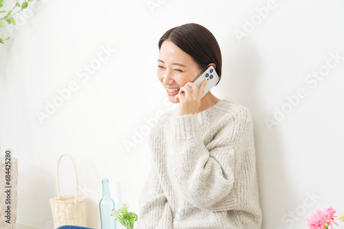リビングでスマホで電話をする女性 photo