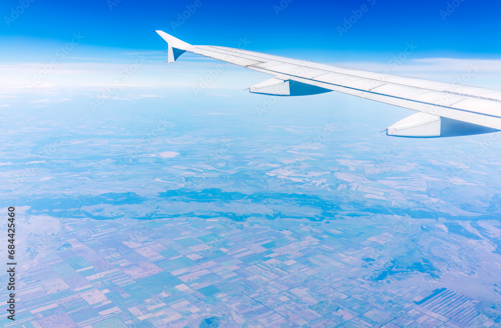 Aerial view from airplane window above green ground. View from the airplane window with beautiful clouds at sunrise Aerial view from airplane window above green ground. View from the airplane window with beautiful clouds at sunrise