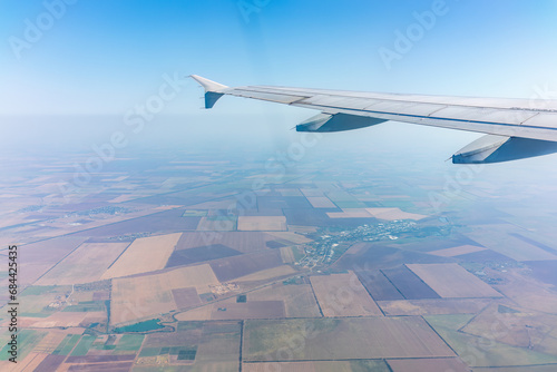 Aerial view from airplane window above green ground. View from the airplane window with beautiful clouds at sunrise