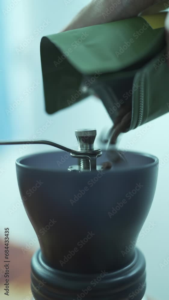 Pouring roasted coffee bean into a coffee grinder Pouring roasted coffee bean into a coffee grinder