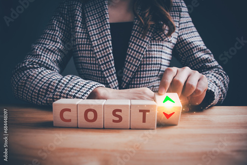 "COST" text on wooden blocks with up and down arrows. Help businesses achieve financial goals and stay profitable. Decreasing costs and cost management, control, reduction, optimization of costs.