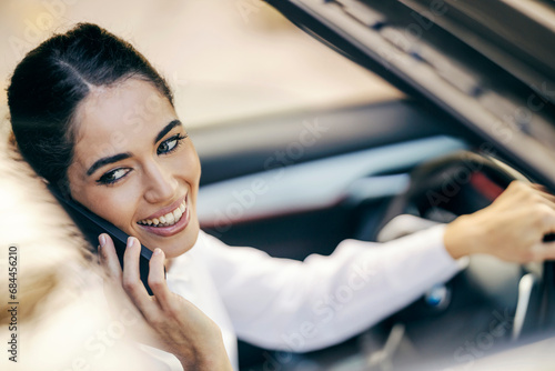 Portrait of a woman having a phone call while driving a car.