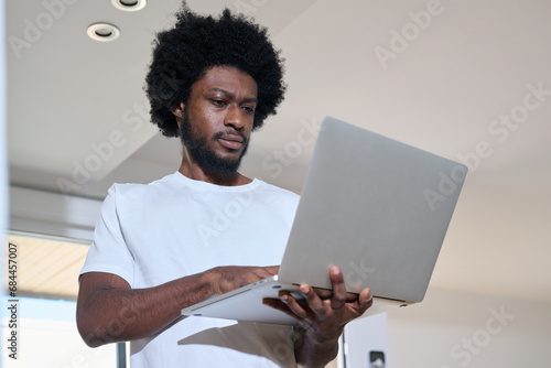 From below, Casual businessman wearing jeans and white t-shirt using laptop at office photo