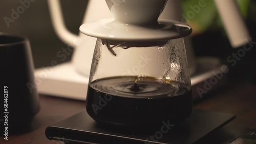 Fresh brew of black coffee drip into glass carafe through ceramic dripper photo