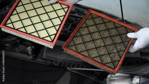mechanic holds a new car air filter to replace the old car filter,Replacing a new air filter in a passenger car