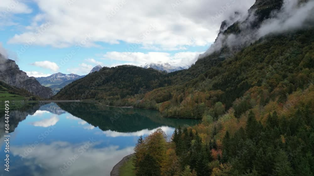 Slow zoom in shot of a lake situated between the forest and trees in the valley Slow zoom in shot of a lake situated between the forest and trees in the valley