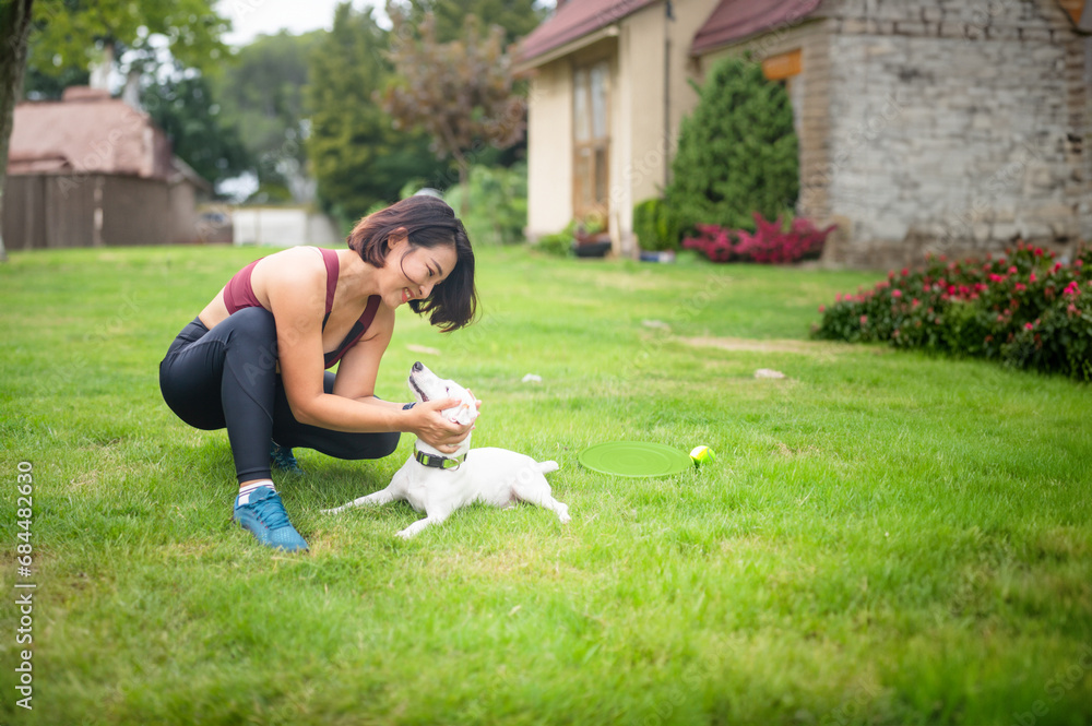 Fototapeta premium Single Asian woman happy with dog shows self-love and enjoy exercising with pets Complete with Frisbee equipment and dog training ball