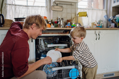 Fotografía Little boy helping father to load dishwasher after breakfast