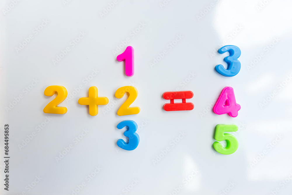 White board with magnetic numbers, primary school math. Solving examples White board with magnetic numbers, primary school math. Solving examples