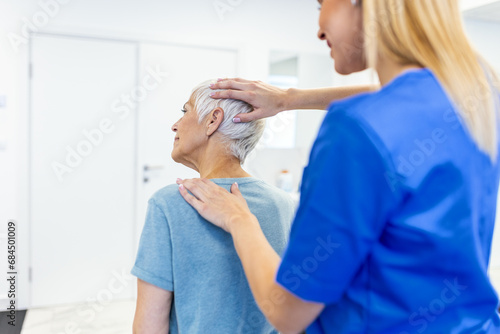 Licensed chiropractor or manual therapist doing neck stretch massage to relaxed female patient in clinic office. Young woman with whiplash or rheumatological problem getting professional doctor s help