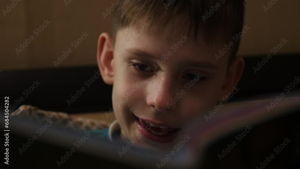 A 10-year-old Caucasian schoolboy reads a book aloud while inside the house. child's leisure time reading interesting and educational books, doing school homework A 10-year-old Caucasian schoolboy reads a book aloud while inside the house. child's leisure time reading interesting and educational books, doing school homework