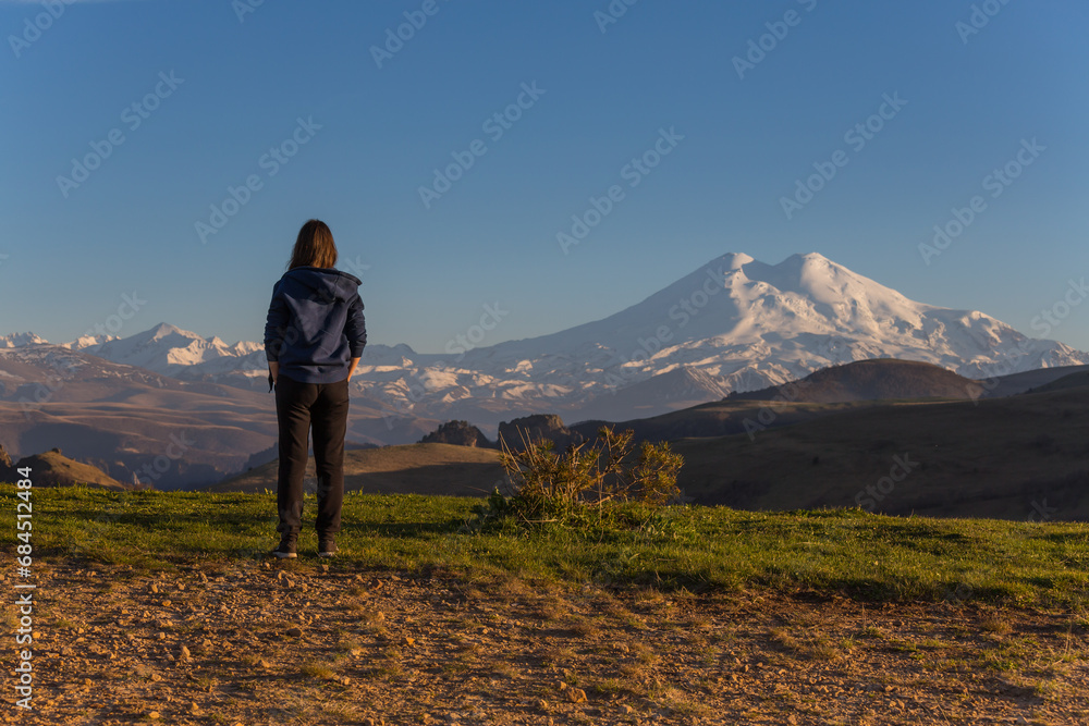 A girl looking at Caucasus mountains on sunset