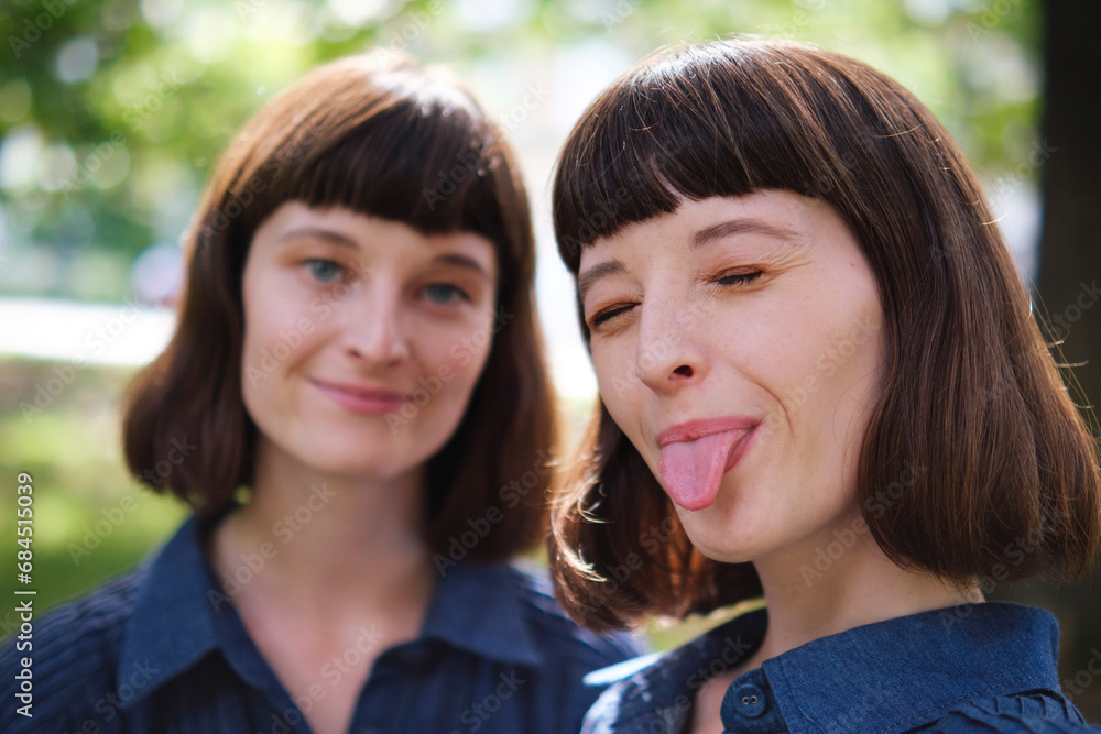 Smiling woman with sister sticking out tongue Smiling woman with sister sticking out tongue