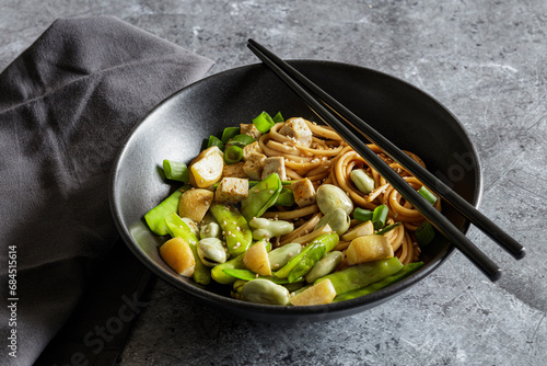 Bowl of vegan miso udon bowl with tofu, snap peas, broad beans and turnips photo