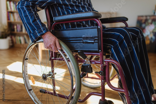Senior man sitting and wheeling wheelchair at home photo