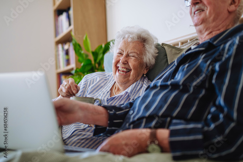 Cheerful senior couple sitting with laptop at home photo