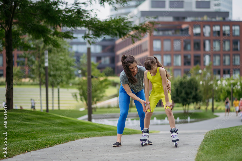 Mother teaches her daughter to roller skate in the city Mother teaches her daughter to roller skate in the city