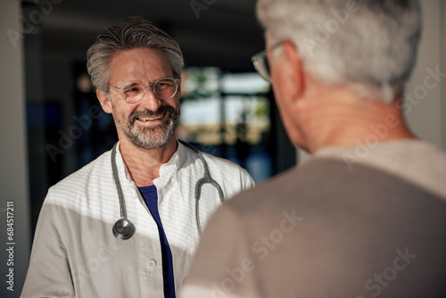 Happy doctor talking to man in hospital photo