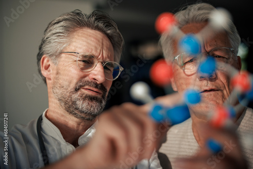 Senior scientist discussing with man over molecular structure photo