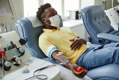 Man wearing protective face mask donating blood photo